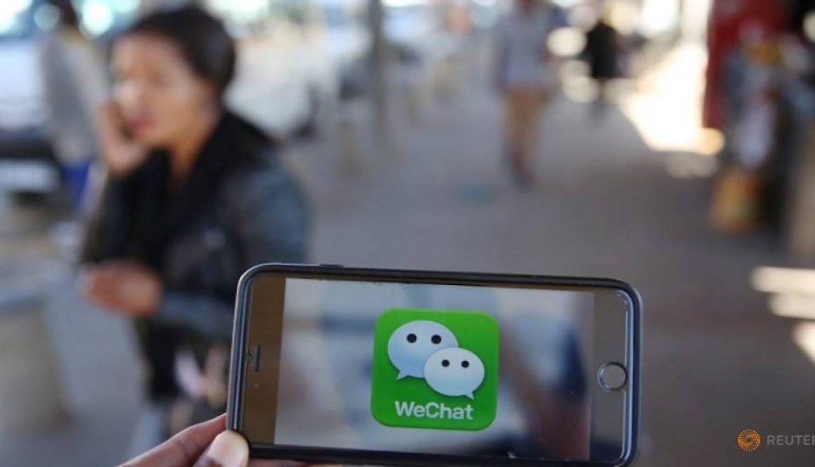 a-wechat-logo-is-displayed-on-a-mobile-phone-as-a-woman-walks-past-as-she-talks-on-her-mobile-phone-at-a-taxi-rank-in-this-picture-illustration-1.jpg